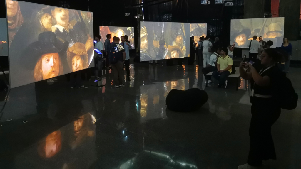 Visitantes observan proyecciones de obras de Rembrandt en la exposición Lienzos Vivos.